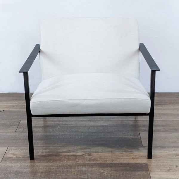 CB2 Cue chair with matte black frame and white textured upholstery, profile view, on wooden floor.