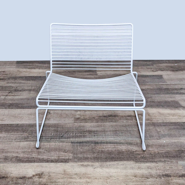 Design Within Reach Hee Lounge Chair - Low wide seat, sturdy steel frame, stackable design on wooden floor.