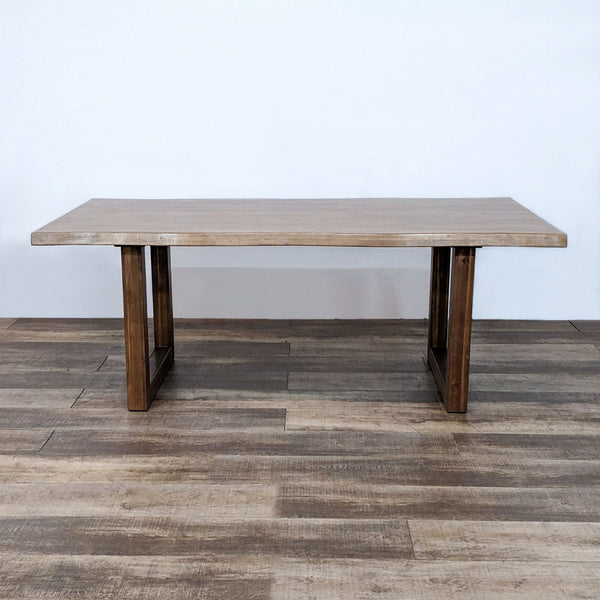 Reperch brand live edge wood top dining table with a sled base against a white wall.