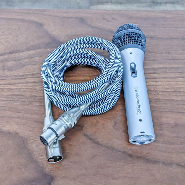 Audio-Technica ATR2100-USB microphone with coiled XLR cable on a wooden surface.