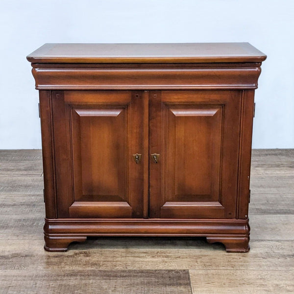 Reperch traditional nightstand with drawer, shelf, and raised panel doors on a wooden floor.