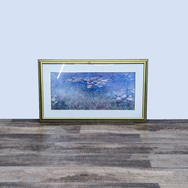 Alt text 1: Framed print of Monet's "Water Lilies" with a blue palette, set against a wooden floor and a light wall, from Reperch.