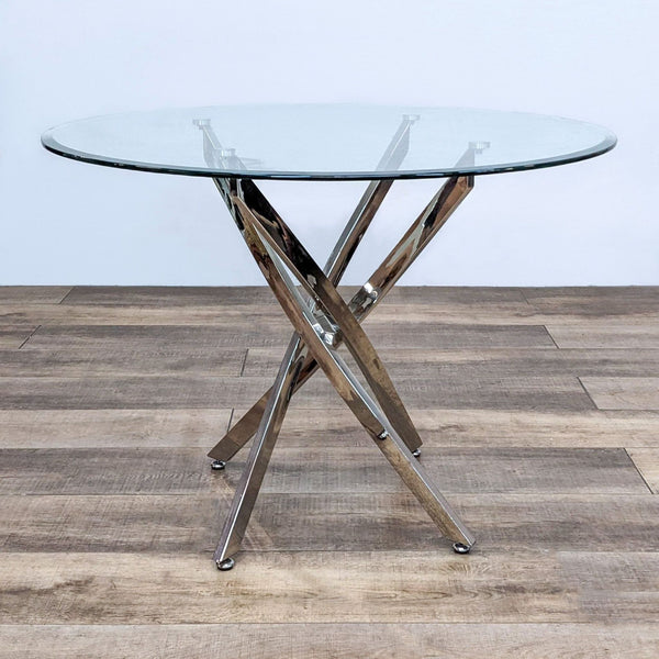 Reperch modern dining table with a clear glass top and sculptural metallic base at an angle, on a wooden floor.