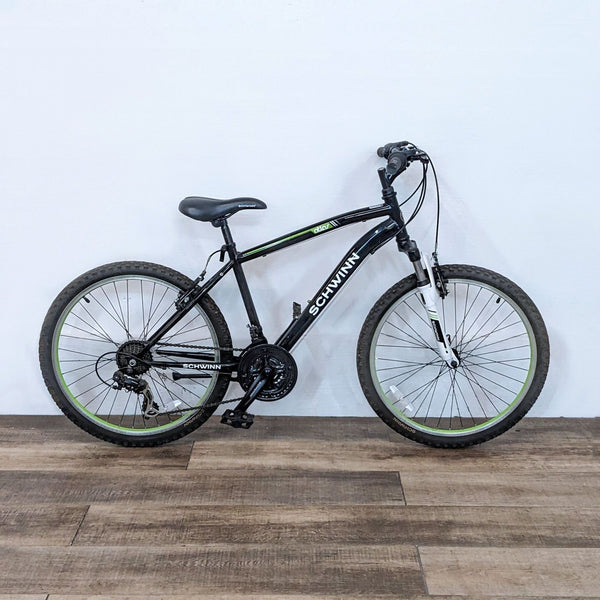 Schwinn mountain bike with a sturdy black frame, designed for off-road riding, featuring green accents and a comfortable saddle.