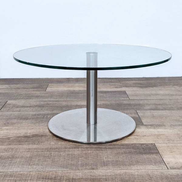 Reperch brand end table with round glass top and metallic pedestal base on wooden floor.
