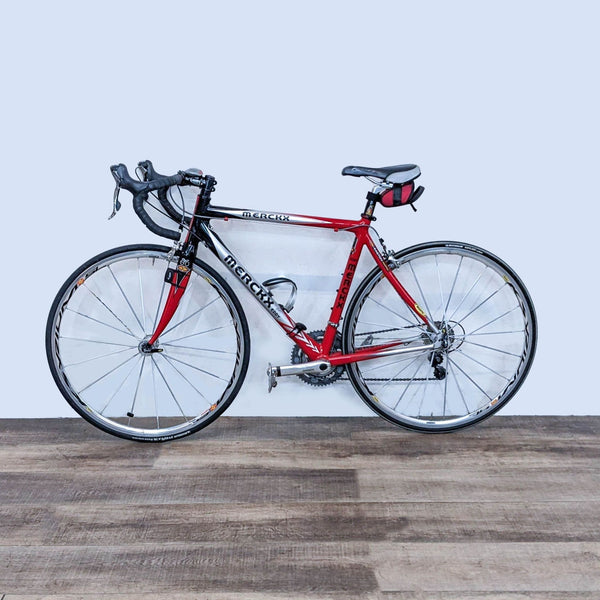 Sleek Eddy Merckx road bike with red and black design, lightweight frame for speed and endurance, standing indoors.