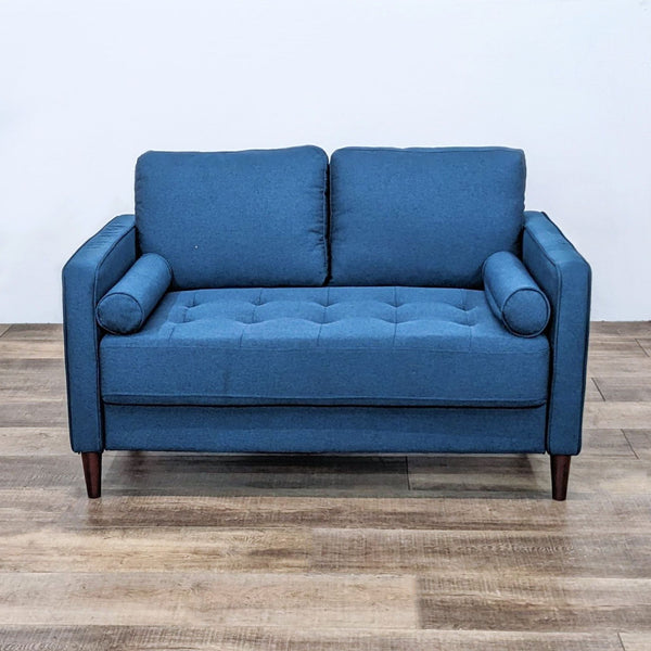 Alt text 1: Blue fabric loveseat by Lifestyle Solutions with tufted bench seat, two bolster pillows, and wooden legs.