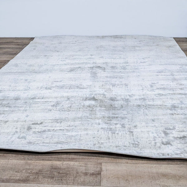 Restoration Hardware 9x12 silk rug with a neutral palette displayed on a wooden floor, exemplifying luxury and comfort.