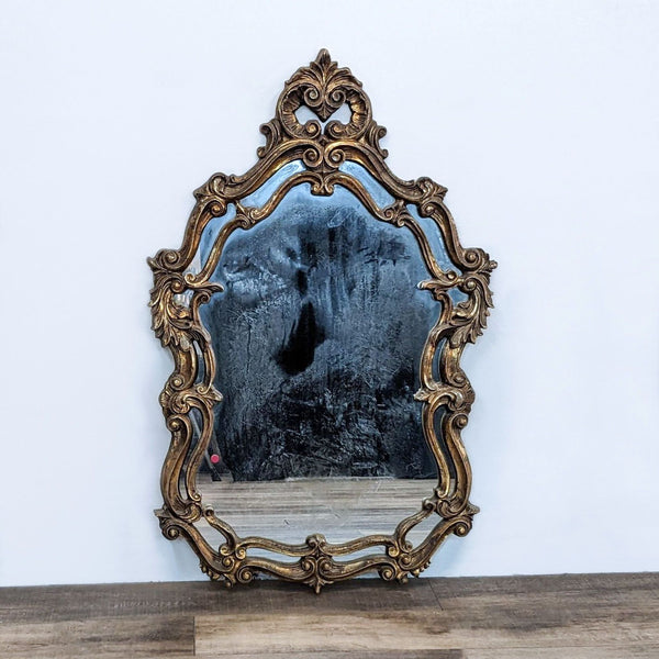 Reperch brand ornate mirror with intricate gold frame on a wall, reflective surface with aged patina.