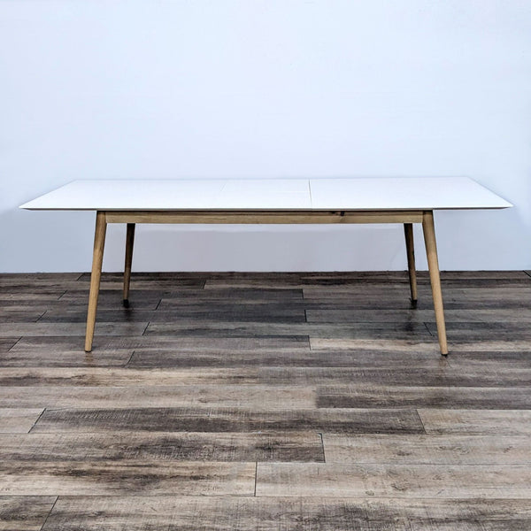 BoConcept Milano white extendable dining table with wooden legs in a minimalistic design, demonstrating its extended form.