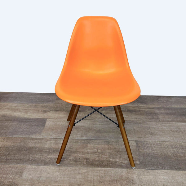 Reperch ergonomic orange dining chair with Eiffel-style wooden legs on a hardwood floor.