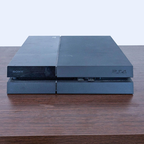 Sony PlayStation 4 console on a wooden surface, sleek black finish, minimalist design, minor wear visible.