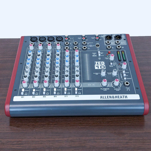 Allen & Heath ZED-10 professional audio mixer on a wooden table, showcasing its control knobs and sliders.