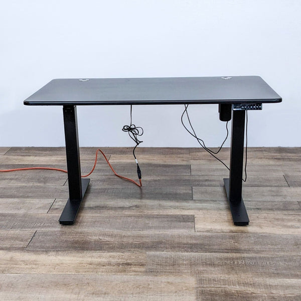 Autonomous black motorized standing desk with steel frame and control panel showing preset heights.