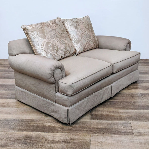 Neutral-tone fabric Loveseat with two back cushions featuring a paisley pattern, set on a wooden floor.