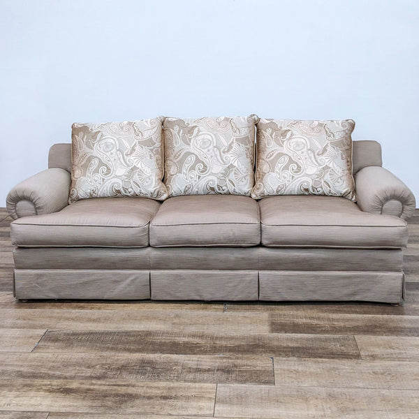 Neutral 3-seat Reperch sofa with patterned cushions, roll arms, and skirt.