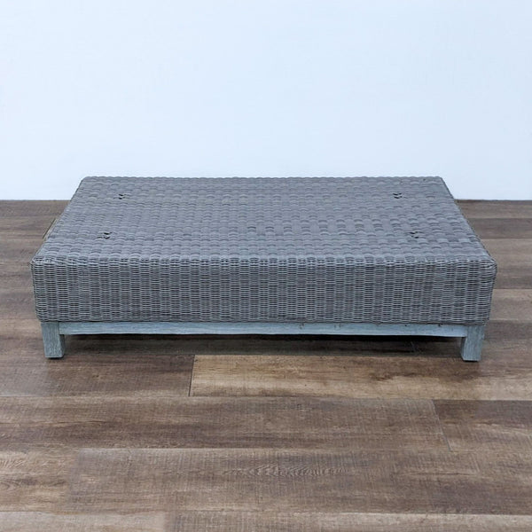 Restoration Hardware low profile wicker coffee table with weathered wood base on a wooden floor.