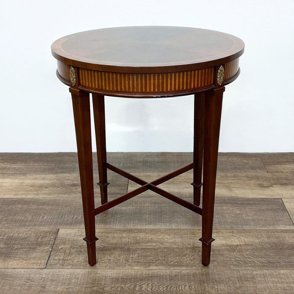 Round Century Furniture end table with inlaid top and metal medallions on a wooden floor.