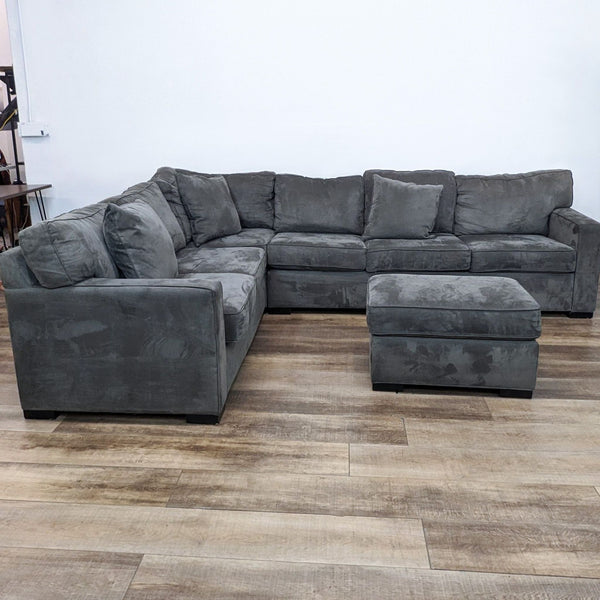 Alt text 1: "Scandinavian Designs' L-shaped sectional sofa in graphite color with small patterns, accompanied by a matching ottoman, set on a wooden floor."