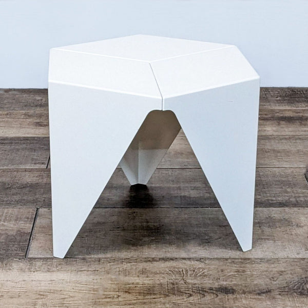 Hexagonal white Vitra Prismatic Side table with a geometric design on a wooden floor.