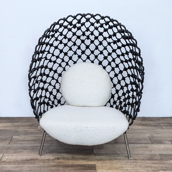 A Reperch Dragnet Lounge Chair with acrylic fabric resembling a fishnet wrapped around a steel frame, set against a plain backdrop.