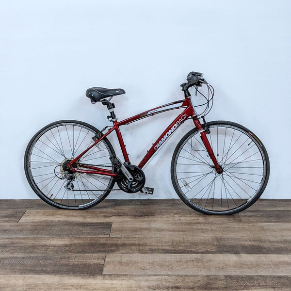 1. Diamondback hybrid bike displayed against a white wall on a wooden floor, featuring a comfortable saddle and smooth gears.