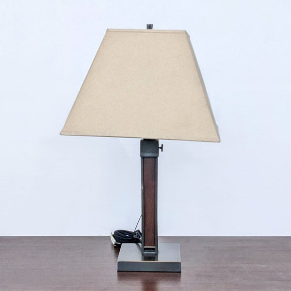 1. Crate & Barrel traditional table lamp with a beige shade and square base on a wooden surface against a white background.
