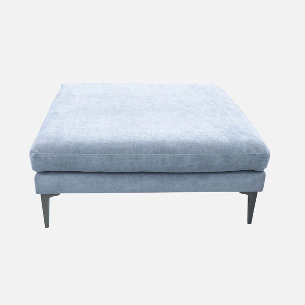 Distressed blue velvet square ottoman on metal legs by West Elm, suitable as a coffee table or seating.