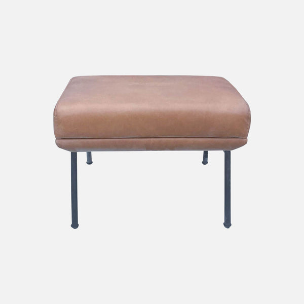 1. West Elm vegan leather ottoman, padded top, with tall metal legs, against a white background.