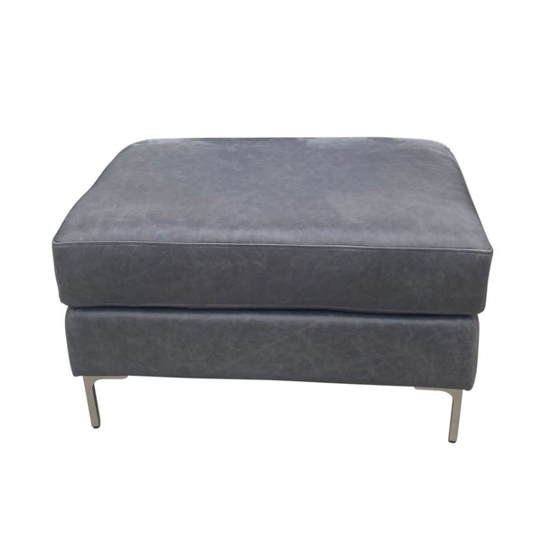 1. A gray Pottery Barn ottoman with a smooth finish and metal legs on a white background.