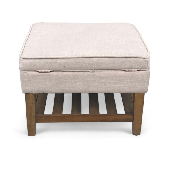Neutral-colored fabric ottoman with a storage compartment on a wooden frame with shelf, by Target.