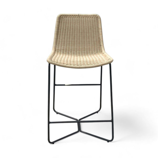 West Elm resin wicker counter stool with sloped seat and black metal frame.