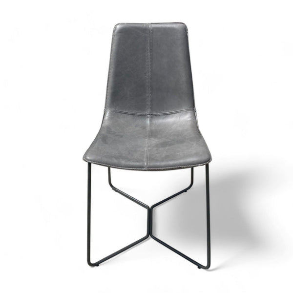 1. "West Elm Slope dining chair with a curved leather seat and a black metal base against a white background."