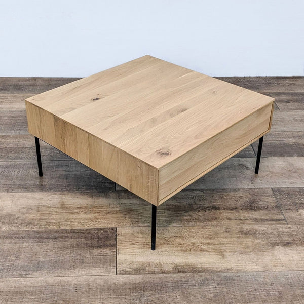 1. A square Industry West coffee table with a light wood finish and sleek black metal legs on a wooden floor.