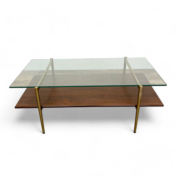 West Elm coffee table with a clear glass top, walnut shelf, and brass-finished metal legs, on a white background.
