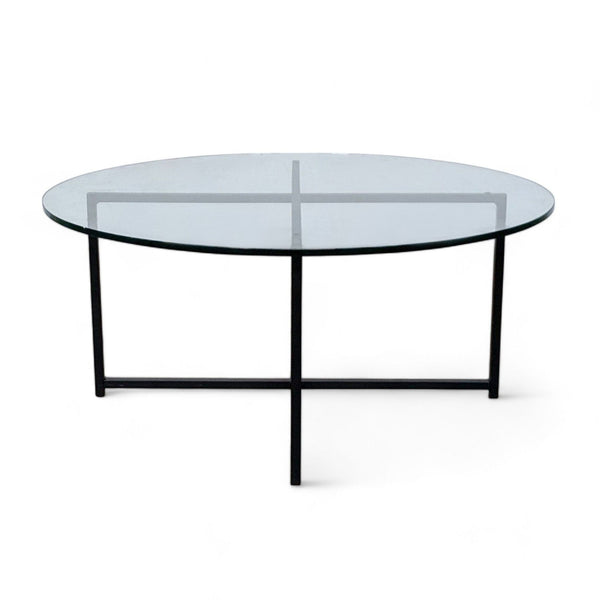 Round glass coffee table with a black metal frame by Room & Board on a white background.