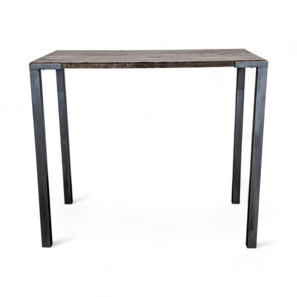 CB2 Stilt counter height dining table with a wooden top and steel frame, showcasing industrial style. 