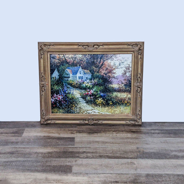 Painting of a white house in a colorful garden landscape, ornate frame, on a wooden floor.