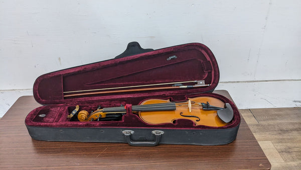 1. Reperch full-size violin with amber finish in open velvet-lined case alongside a wooden bow, against a white wall on a wooden floor.