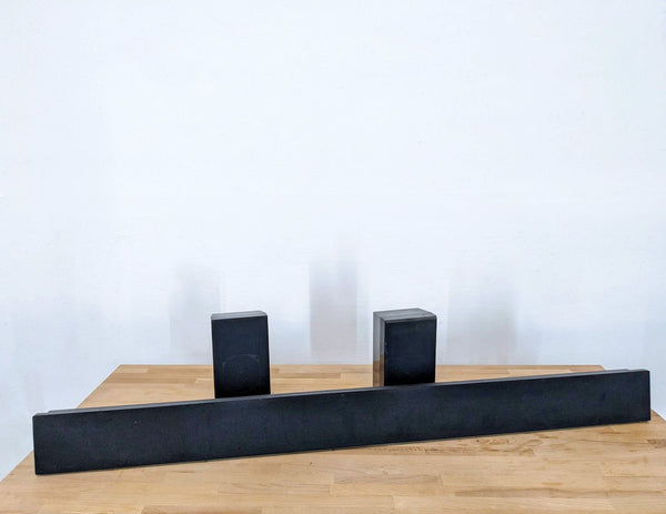 Leon soundbar and two satellite speakers on a wooden floor against a white wall.