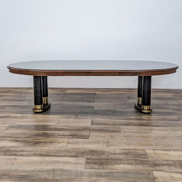 Oval cherry dining table by Stanley Furniture, with black double pedestal base and brass trim, without leaves.
