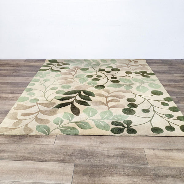 Handcrafted Nourison area rug with carved leaves and branches on a vanilla background displayed on a wooden floor.