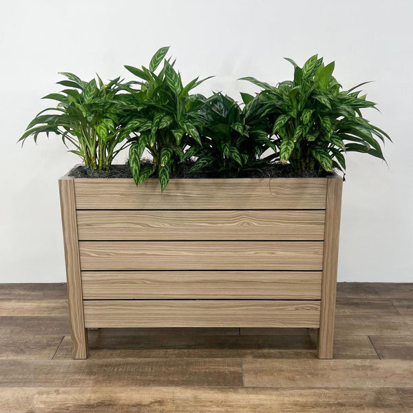 OFS Intermix planter with green plants, solid wood slat design on a wooden floor.