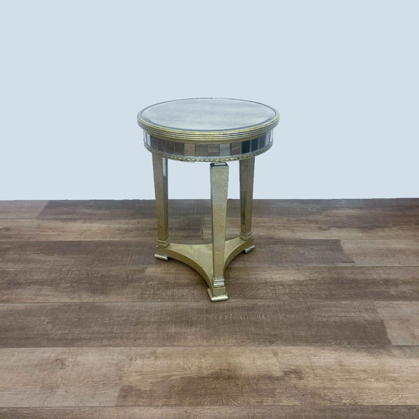 Round mirrored side table by Reperch with wood frame on a wooden floor, facing front.