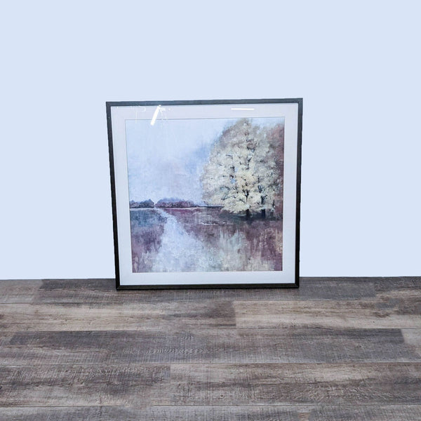 Framed landscape painting by Art.com with misty trees and water reflection, leaned against a wall on a wooden floor.