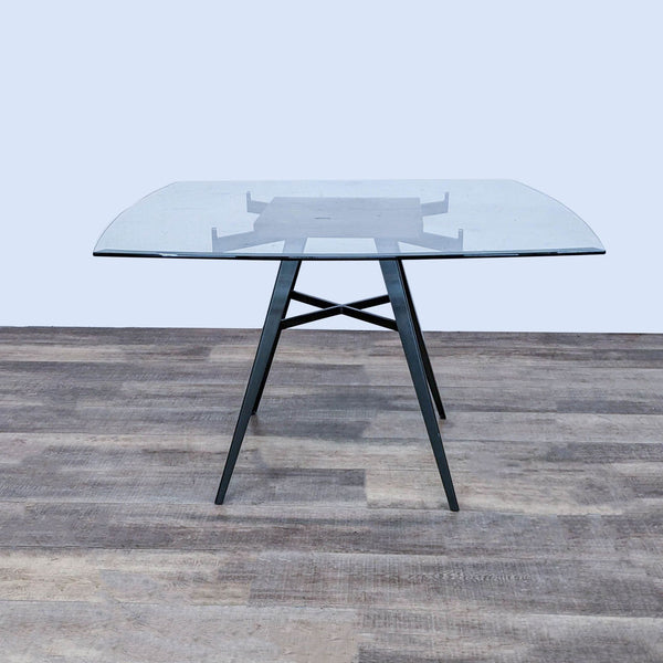 Armen Living Ojai dining table with clear tempered glass top and stylized mineral finish metal base on a wooden floor.