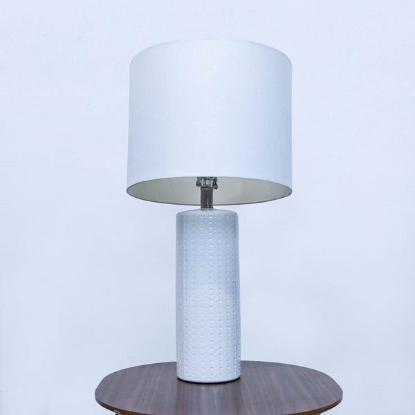 Reperch branded white table lamp with cylindrical textured base and plain drum shade on a wooden table.