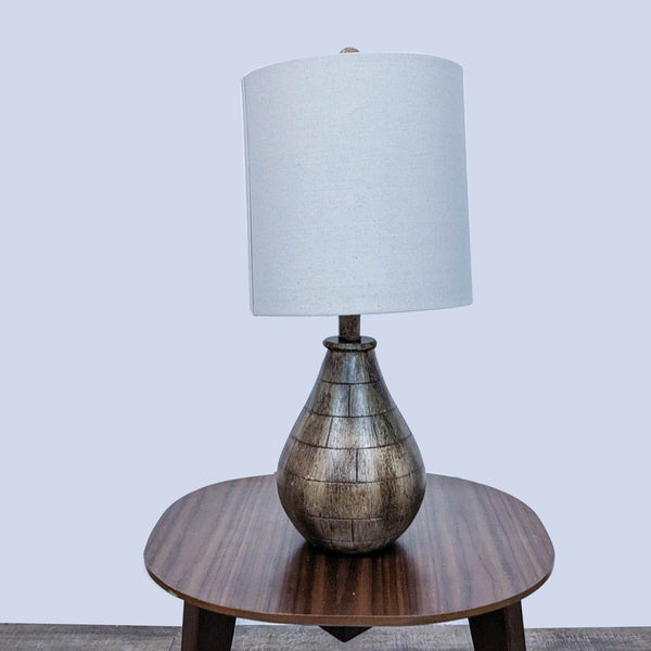 Reperch brand table lamp with a round white shade and a tapered wooden base on a brown table against a gray backdrop.
