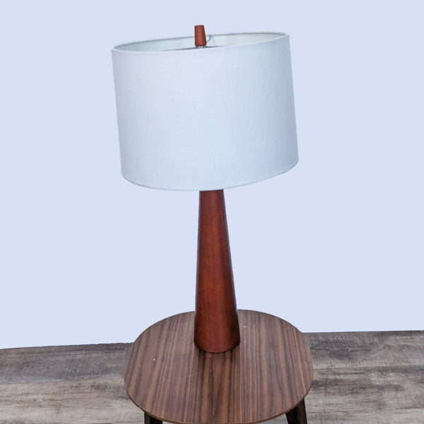 Reperch brand table lamp with white shade and wooden base on a table.