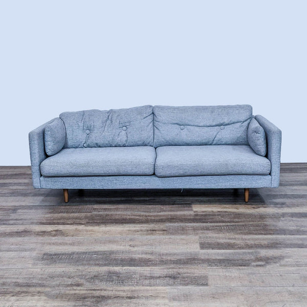 Alt text 1: A front-facing view of an Article-brand 3-seat sofa featuring a clean line design, Anton Winter gray fabric, button back cushions, and walnut finish feet on a wooden floor.